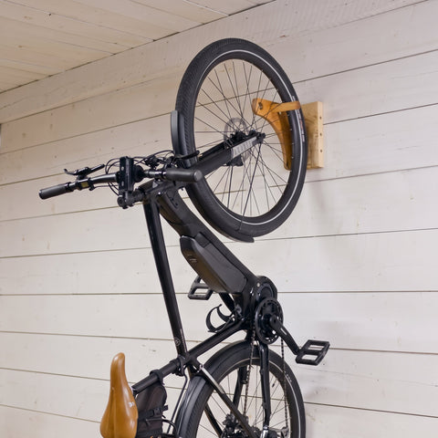 Support mural vertical en érable massif avec un vélo suspendu par la roue, fabriqué au Québec.